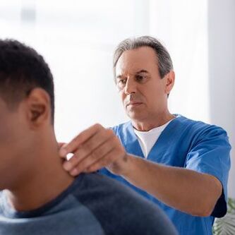 A doctor performs a diagnostic examination on a patient with neck pain.
